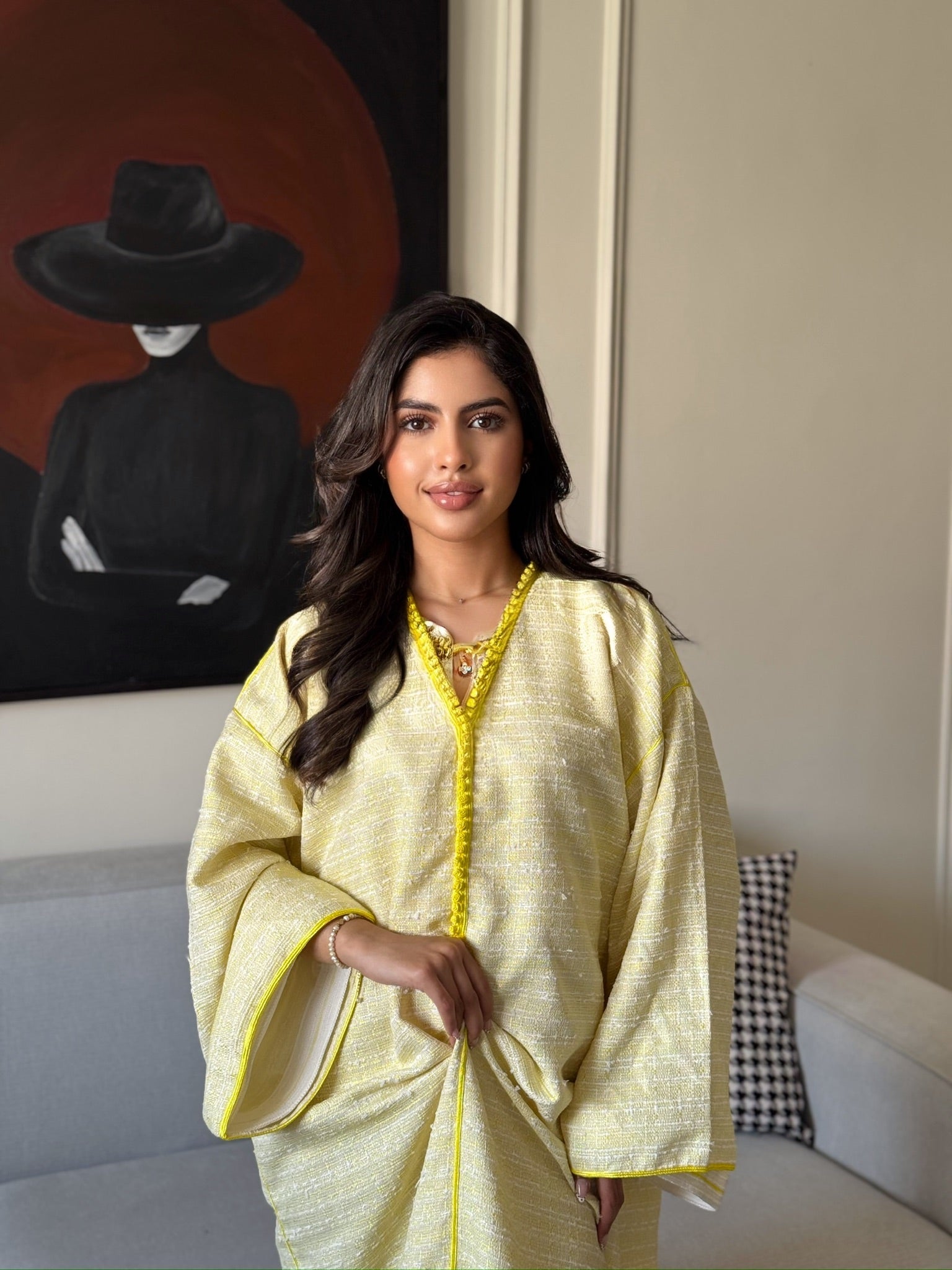 Woman wearing a yellow luxury caftan with wide sleeves and embroidered details