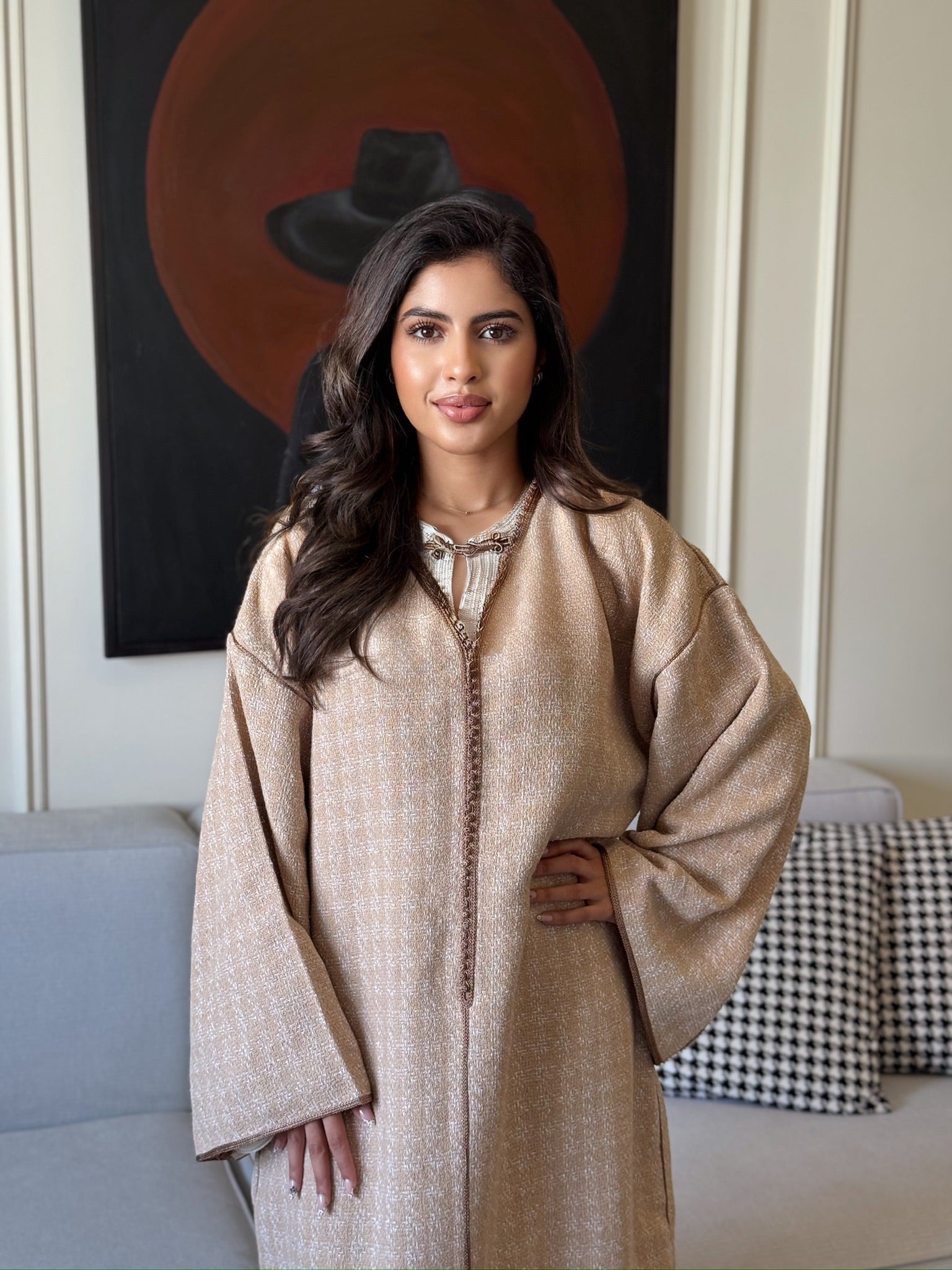 Woman wearing a beige caftan with wide sleeves and a flowing silhouette