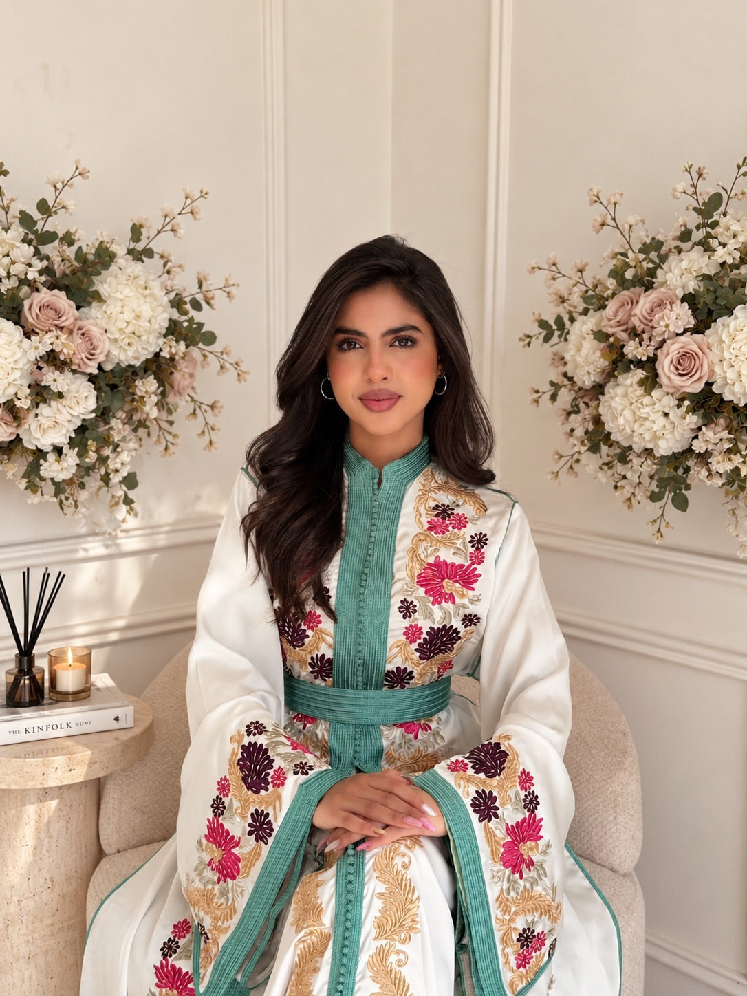 Model seated in ivory Takchita Lamis with colourful floral embroidery and turquoise neckline trim