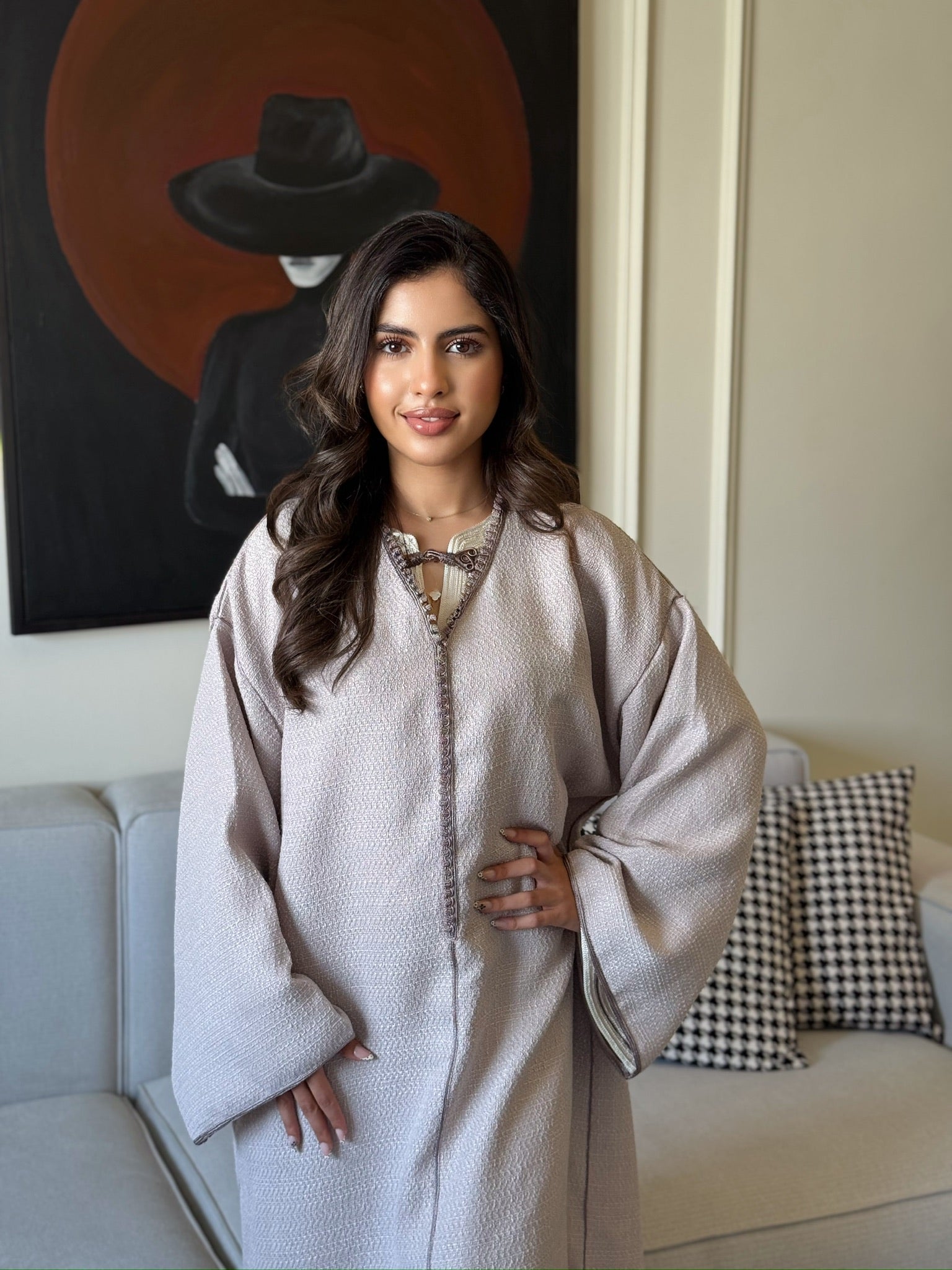 Woman wearing a light beige caftan with wide sleeves and a flowing silhouette