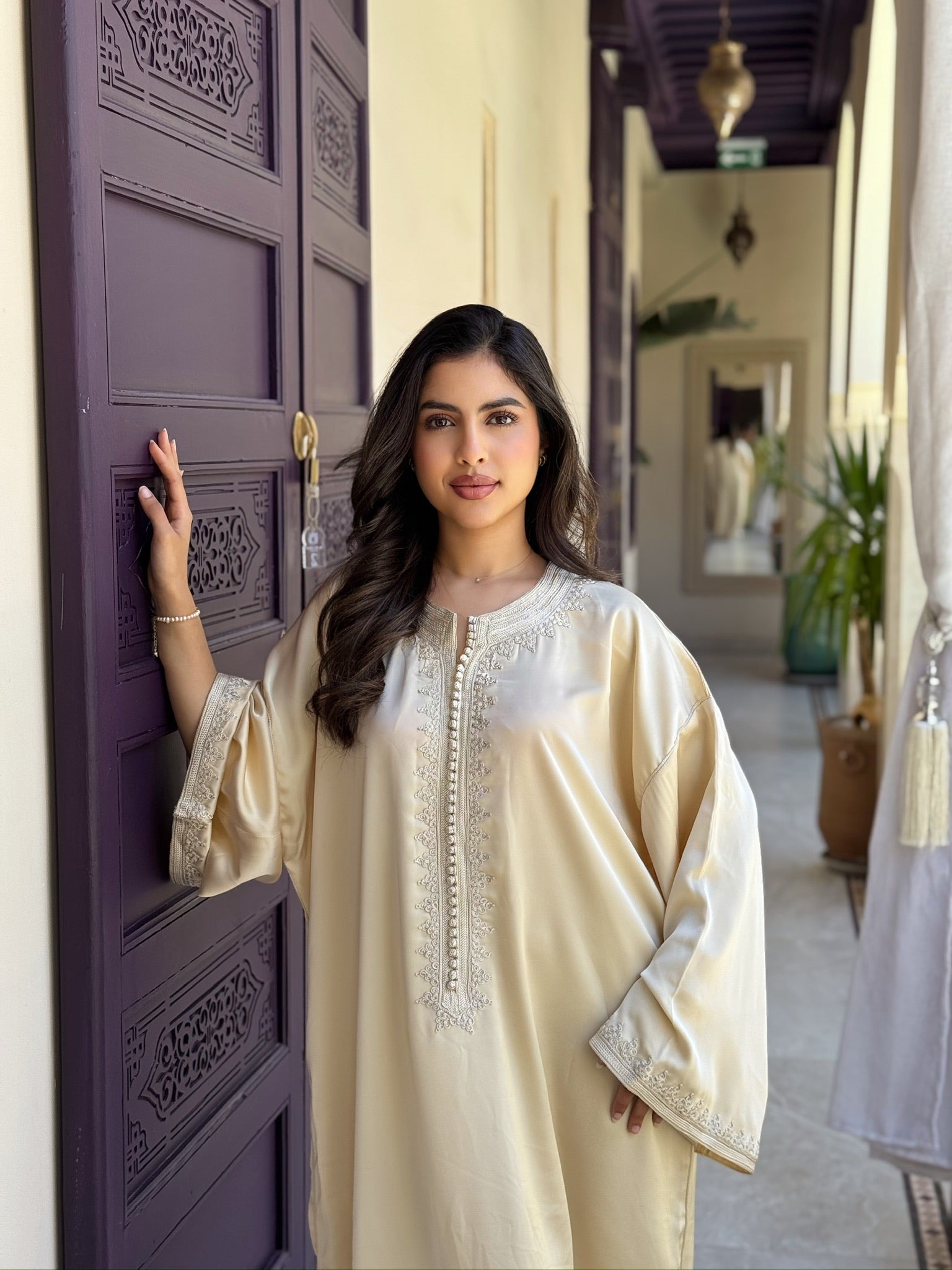 Woman wearing an ivory gandoura with elegant embroidery and flowing sleeves