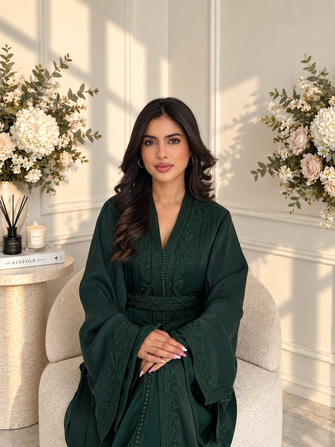 Model seated in deep green Takchita Ayah with tonal embroidery along the neckline and wide cuffs