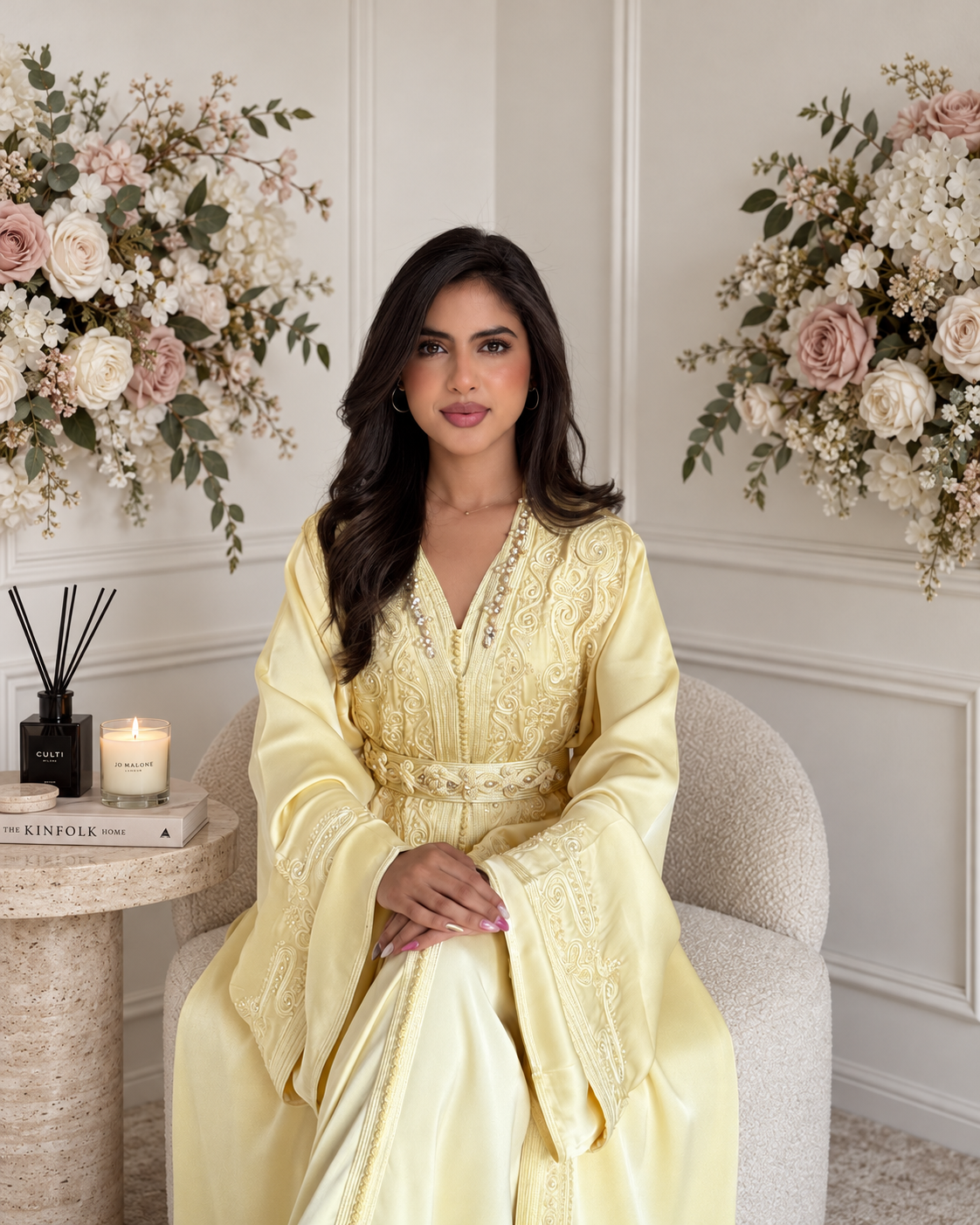Model seated in pale yellow Takchita Mayssa with an embroidered bodice, wide cuffs and matching belt
